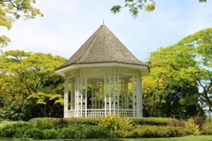 A picturesque white gazebo surrounded by vibrant green trees and well-manicured bushes.